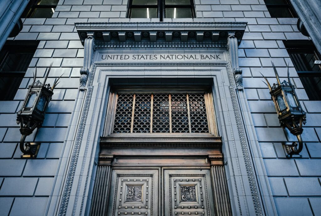 From below classic styled historic building of United States National Bank with wooden doors and vintage lanterns located in Portland, Best Banks For Ecommerce Business